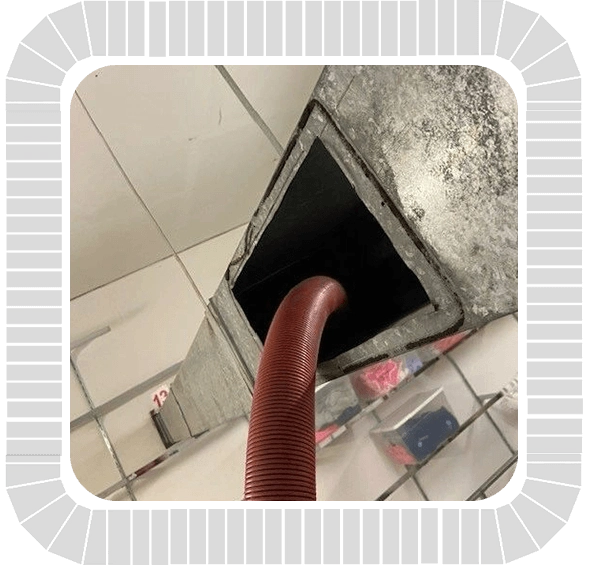 A ventilation cleaning in a room with a red hose.